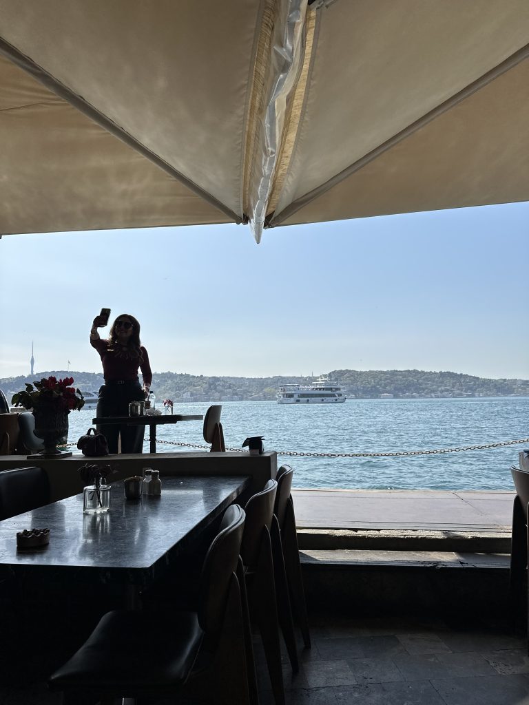 an influencer taking a selfie at the waterfront of at the ortakoy cafe
